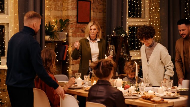 Warm family gathering at festive dinner table with candles and decorations, celebrating the holiday season.